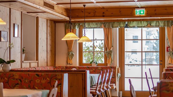 A cozy restaurant with wooden walls and colorful benches. Daylight streams through the windows, inviting you to linger. - Hotel Gasthof Zwieselstein - Zwieselstein