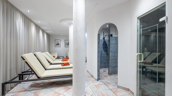 A modern wellness area with loungers and a steam bath. The elegant atmosphere is emphasized by bright colors and soft lighting. - Hotel Gasthof Zwieselstein - Zwieselstein