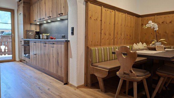 A cozy kitchen with wooden furniture and a seating area.  
It is bright and inviting, perfect for shared meals. - Landhaus Alpenjäger - Zwieselstein