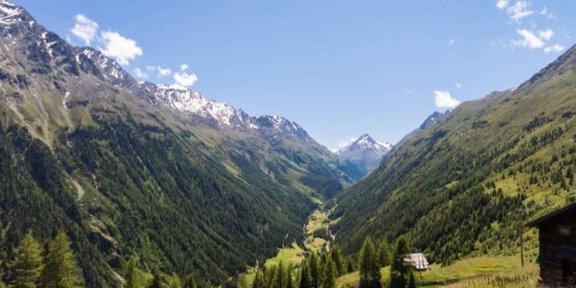 Eine wunderschöne Berglandschaft mit hohen, grünen Hügeln und schneebedeckten Gipfeln. Der Himmel ist klar und blau, was die malerische Szene vervollständigt. - Hotel Silbertal - Sölden