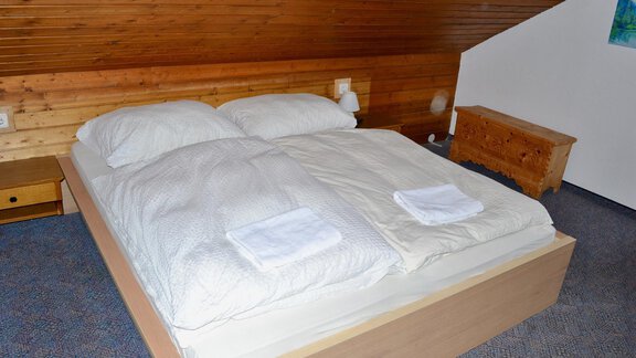 A cozy bedroom with a large double bed and fresh towels. The walls are made of wood, creating a warm atmosphere. - Haus Maria - Hochsölden
