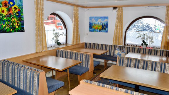 A cozy restaurant with benches and tables. The windows offer a view of a snowy landscape. - Haus Maria - Hochsölden