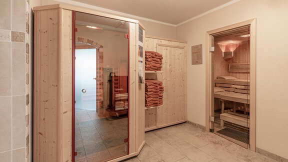 Ein gemütlicher Wellnessbereich mit einer Sauna aus Holz und gefalteten Handtüchern. Die Wände sind hell gefliest und schaffen eine entspannende Atmosphäre. - Apart Felsenhof - Huben