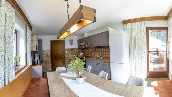 A cozy breakfast table with fresh rolls, fruit, and beverages. The room has large windows overlooking nature. - Berghof Reich - Längenfeld