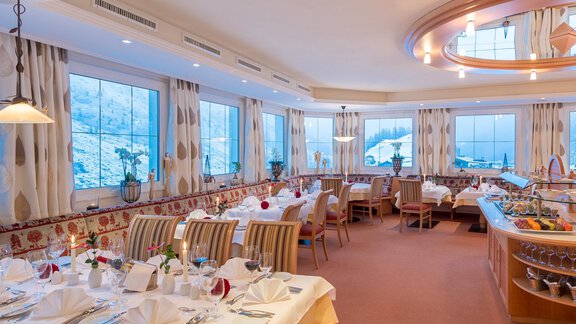 An elegant restaurant with table decoration and a view of the snowy landscape. Large windows let in plenty of light and create an inviting atmosphere. - Hotel Olympia - Obergurgl 
