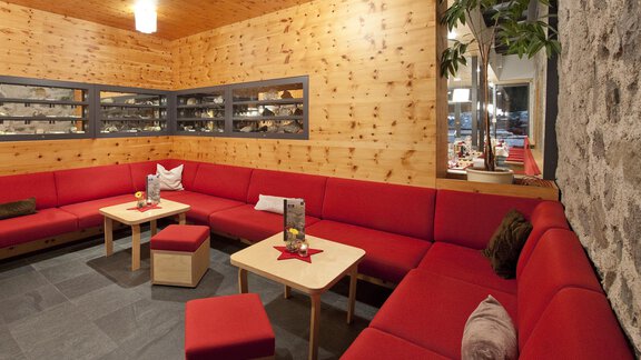 A cozy room with a red sofa and wooden walls. Tables and decorative plants create an inviting atmosphere. - Universitätszentrum Obergurgl - Obergurgl 