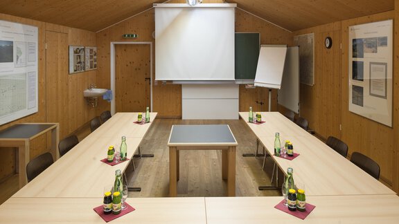 A conference room with wooden walls and a large table in the center. On the table, there are glasses of water and notepads ready. - Universitätszentrum Obergurgl - Obergurgl 