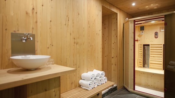 A modern lounge interior with cozy white benches and red cushions. Wooden stools and soft lighting create a relaxed atmosphere. - Universitätszentrum Obergurgl - Obergurgl 