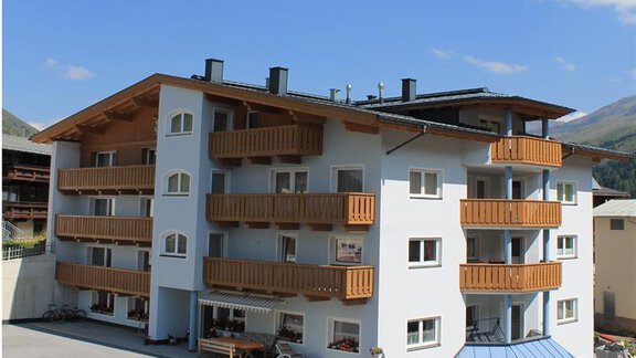 A modern building with several balconies and a clear blue sky. The facade is white with wood cladding. - Haus Martinshof - Obergurgl 
