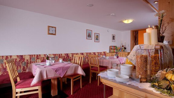 A cozy dining area with red tables and wooden chairs. The atmosphere is friendly and inviting, perfect for a relaxed meal. - Haus Martinshof - Obergurgl 