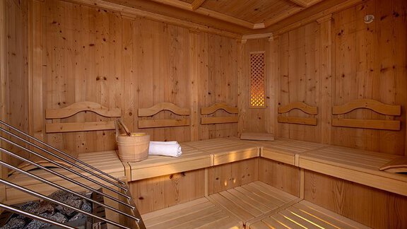A cozy sauna room with wooden benches and a stove. The walls are clad in light wood, creating a relaxing atmosphere. - Haus Martinshof - Obergurgl 