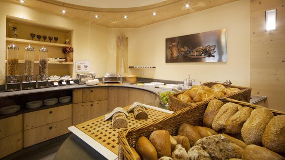 A cozy breakfast nook with fresh rolls in a basket and a wooden counter. The warm lighting creates an inviting atmosphere. - Schönblick Gurgl - Obergurgl 