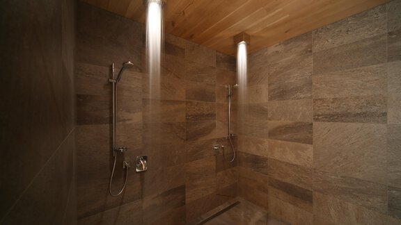 A modern shower room with natural stone walls and a wooden ceiling. Soft lighting creates a relaxing atmosphere. - Schönblick Gurgl - Obergurgl 