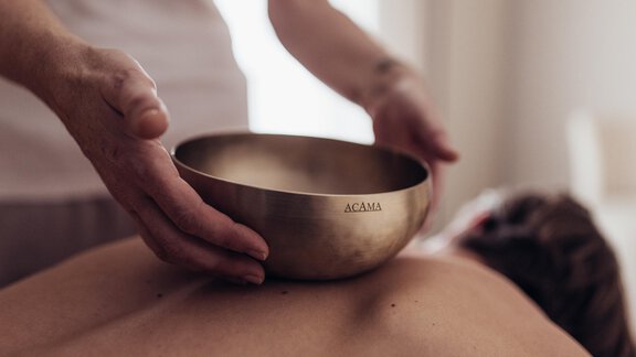 Eine Person erhält eine Klangschalenmassage. Die entspannende Atmosphäre fördert das Wohlbefinden. - Hotel habicher hof - Oetz