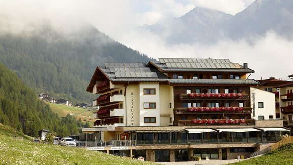 Ein charmantes Hotel mit einem modernen Design, umgeben von Bergen und grünen Wiesen. Die Terrassen sind mit Blumen geschmückt und bieten einen malerischen Ausblick. - Alpengasthof Grüner - Sölden