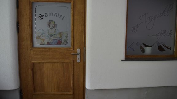 A wooden door with a window displaying the word "Summer." Next to it is a window featuring a picturesque mountain landscape. - Am Trogwohl - Sölden