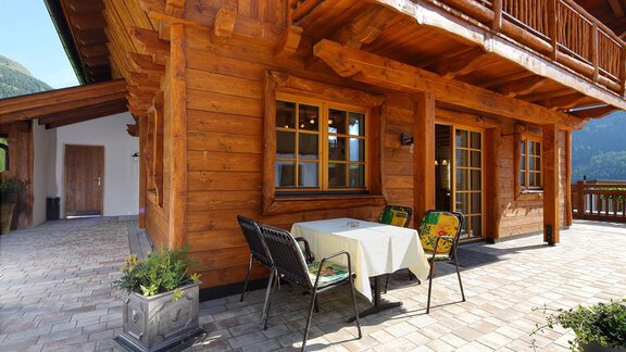 Eine gemütliche Terrasse mit einem Holzhaus im Hintergrund. Es gibt einen Tisch und Stühle sowie einen Blick auf die umliegende Natur. - Andis Almdorf - Sölden