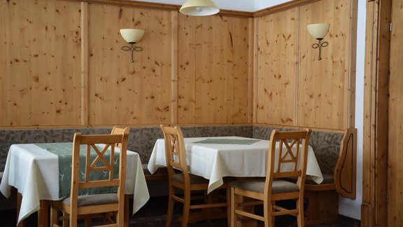 A cozy dining area with wooden walls and simple tables. The seating is rustic and inviting. - Andis Almdorf - Sölden