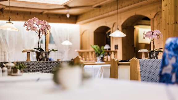 A cozy restaurant with wooden interiors. Orchids are on the tables and the atmosphere is warm and inviting. - Andre Arnold - Boutique Hotel - Sölden