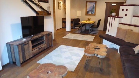 Ein modernes Wohnzimmer mit Holzfußboden und gemütlicher Einrichtung. Es gibt eine Couch, einen TV und einen Esstisch mit Stühlen. - Apart 55 - Sölden