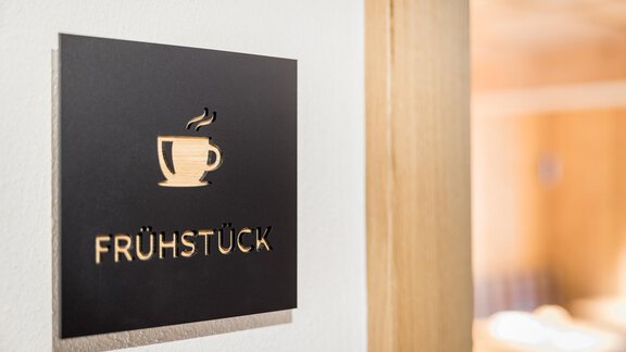 A sign reading "BREAKFAST" and a cup of coffee. It shows the entrance to a breakfast room. - Apart Garni Enzian - Sölden
