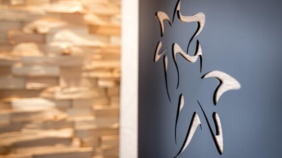 A decorative wall design featuring a woodcut illustration. The background consists of light stones that create a natural atmosphere. - Apart Garni Enzian - Sölden