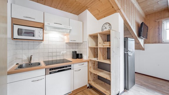 A modern kitchen with functional appliances and wooden shelves. The room is bright and inviting. - Apart Holiday - Sölden