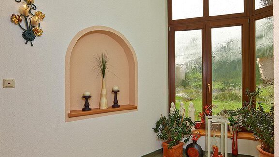 A bright entrance area with large windows and a view of greenery. On a shelf, there are candles and decorative plants. - Apart Marcell - Sölden