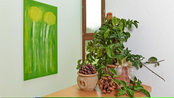 A bright room with a green painting of flowers and a houseplant on the table. There are also decorated pots with pine cones. - Apart Marcell - Sölden