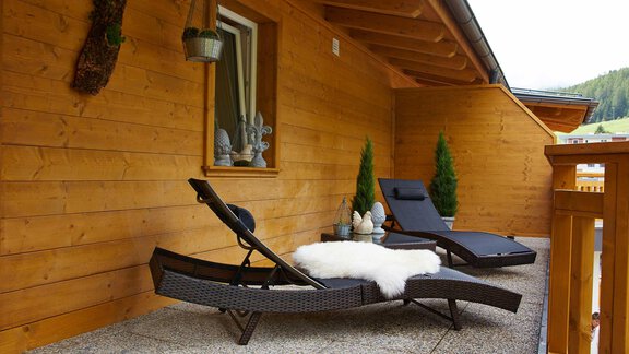 Ein gemütlicher Balkon mit zwei Liegestühlen und einem weichen Fell. Die Holzverkleidung und Pflanzen schaffen eine einladende Atmosphäre. - Alpen Diamond Top 100 | 300 | 700 - Sölden