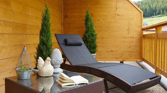 Ein gemütlicher Balkon mit einem Liegestuhl und einem kleinen Tisch. Daneben stehen grüne Pflanzen und dekorative Elemente. - Alpen Diamond Top 100 | 300 | 700 - Sölden