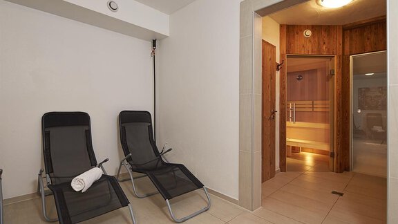 Ein entspannender Wellnessbereich mit zwei Liegen und einem Zugang zur Sauna. Die Wände sind hell und der Raum wirkt einladend. - Alpen Diamond Top 100 | 300 | 700 - Sölden