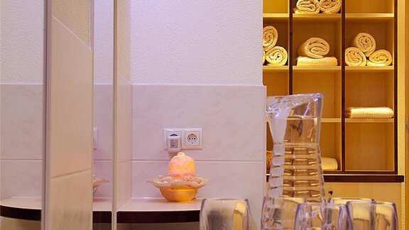 A modern bathroom area with a mirror, glasses on a table, and a shelf with neatly folded towels. The lighting is soft, creating an inviting atmosphere. - Appartement Alpin - Sölden