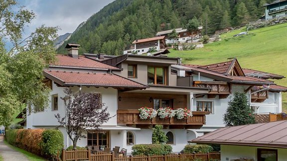 A charming building in the mountains, surrounded by green meadows and trees. The well-maintained path leads closer to the front door. - Appartement Cristallo - Sölden