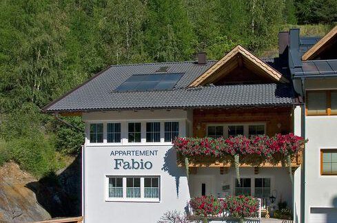 A charming apartment building named "Fabio" amidst green nature. The balconies are adorned with colorful flowers and the building features modern architecture. - Appartement  Fabio - Sölden
