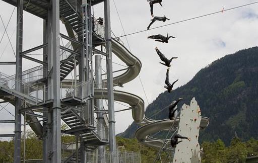 A group of athletes jumps from a high tower into the water. In the background, a climbing wall and spectators can be seen. - Appartement  Fabio - Sölden