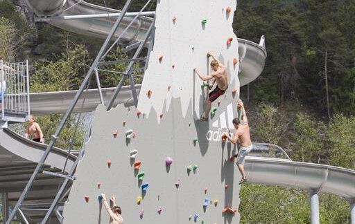 A climbing wall with several climbers. In the background, there are water slides and a lake. - Appartement  Fabio - Sölden
