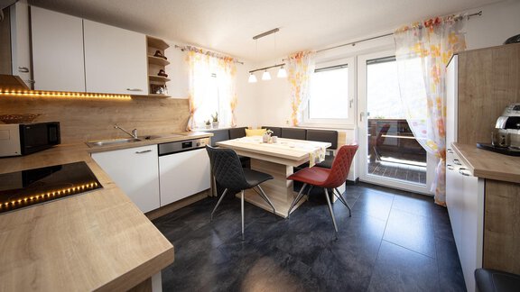A modern kitchen with bright furniture and a dining area. Large windows provide plenty of daylight. - Appartement Harmonie - Sölden