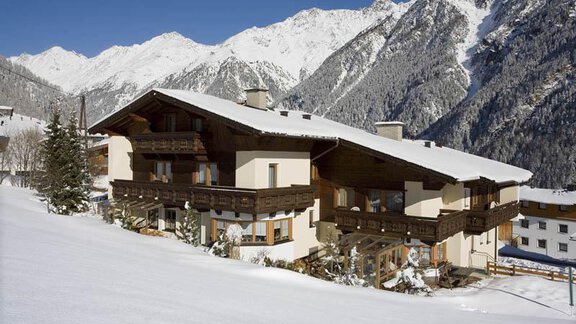 A picturesque chalet in the snow with majestic mountains in the background. The scene radiates tranquility and winter beauty. - Appartement Rangger - Sölden