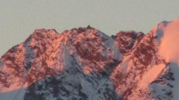 A snow-covered mountain with reddish glowing rocks in the sunlight. The scenery conveys a calm and majestic atmosphere. - Appartement Schwalbennest - Sölden