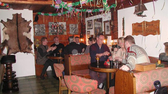 A cozy bar with several people chatting and enjoying drinks. The walls are adorned with pictures and decorative elements. - Appartementhaus Karlinger - Sölden