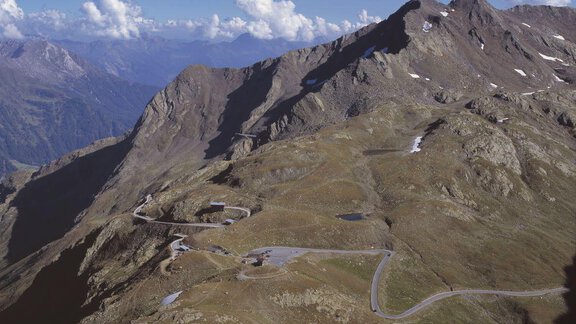 An impressive mountain landscape with steep slopes and expansive views. The road winds through the alpine scenery under a clear sky. - Appt. Gisela - Sölden