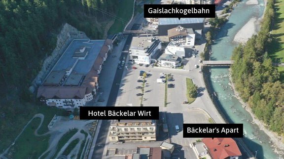 Eine Luftaufnahme eines kleinen Dorfes mit Hotels und Ferienwohnungen. Der Fluss fließt neben den Gebäuden, umgeben von grünen Hügeln. - Bäckelar Wirt - Sölden