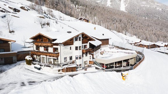 A cozy building in the snow, surrounded by a winter landscape. Snow-covered mountains can be seen in the background. - Belledonne Ski in & out Appartements - Sölden
