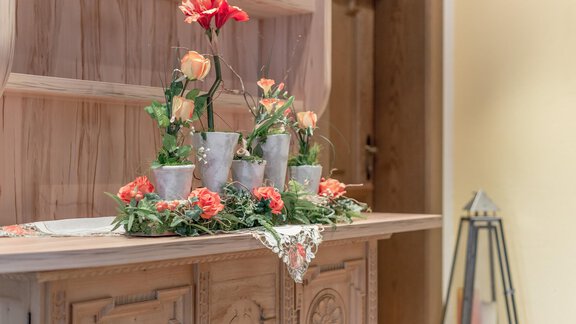 A decorative table with flower pots and fresh flowers. The harmonious arrangement creates an inviting atmosphere. - Ferienhaus Apart Sonnzeit - Sölden