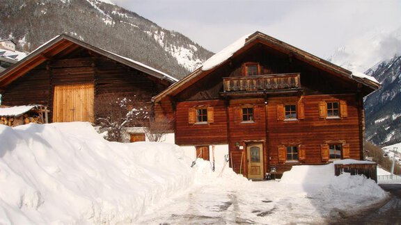A charming wooden house in the snow with a picturesque mountain backdrop. The surroundings are wintery and peaceful. - Ferienhaus Karlingerhof - Sölden