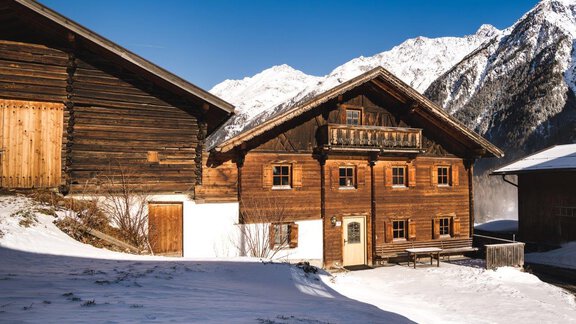 A cozy wooden apartment in a winter landscape. Snow-covered mountains are visible in the background. - Ferienhaus Karlingerhof - Sölden