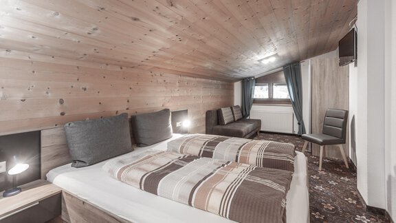 A cozy bedroom with a wooden ceiling and two beds. The decor is modern and the atmosphere is inviting. - Gästeheim Schmiedhof - Sölden
