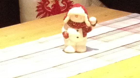 A decorative snowman figure stands on a wooden table. In the background, a pillow with vibrant patterns is visible. - Haus Almrausch - Sölden