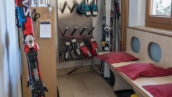 A ski room with various skis and snowboard equipment. There are benches to sit on and a window seat with plenty of daylight. - Haus Almrausch - Sölden